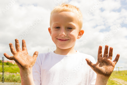 Child playing outdoor showing dirty muddy hands. © Voyagerix