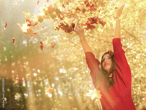  woman relaxing in autumn park throwing leaves up in the air