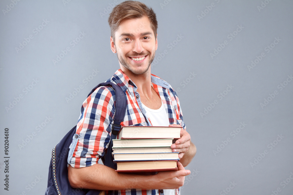 Positive student holding books  - obrazy, fototapety, plakaty 