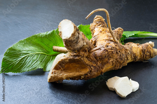 Tablou canvas Washed horseradish root, peeled slices and green leaf