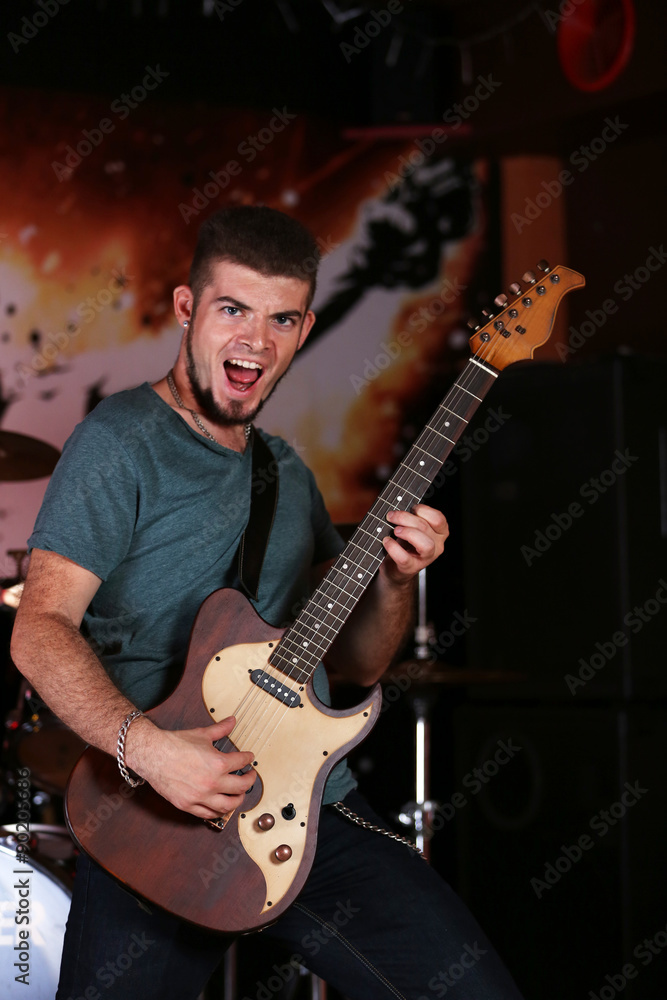 Obraz premium Young man playing on electric guitar at pub