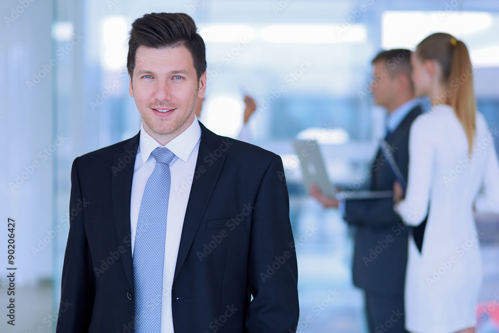 Portrait of young businessman in office with colleagues in the Portrait of young businessman in office with colleagues in the