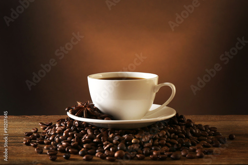 Cup of coffee with grains on wooden table on dark background © Africa Studio