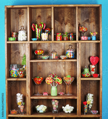 Colorful candies in jars on wooden shelves  close-up