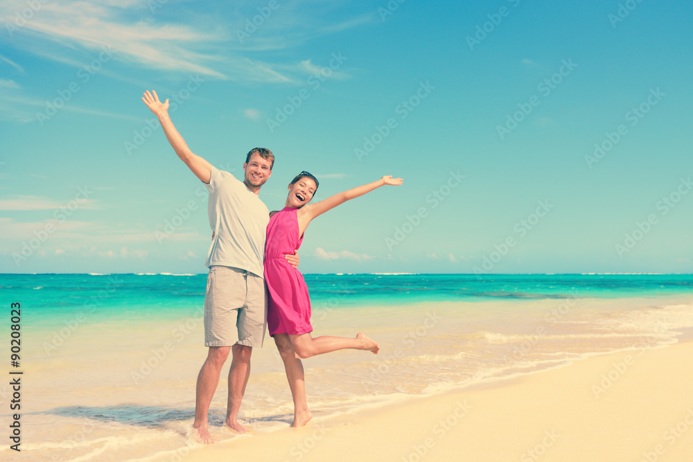 Happy Couple With Arms Raised Standing At Beach Happy Couple With Arms Raised Standing At Beach
