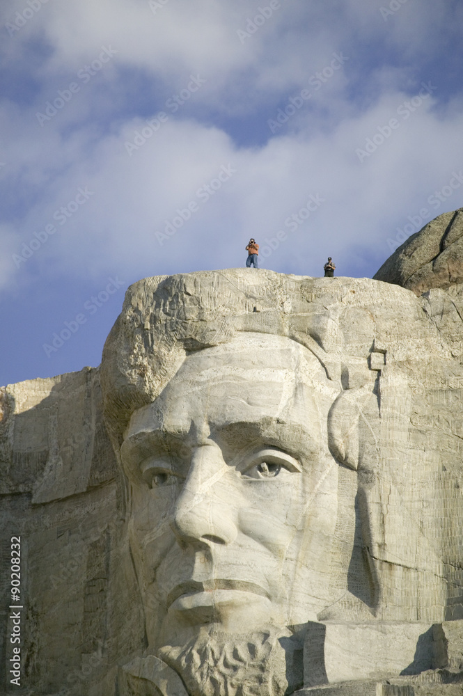 Fototapeta premium A park ranger and photographer standing above Abraham Lincoln at Mount Rushmore National Memorial, South Dakota