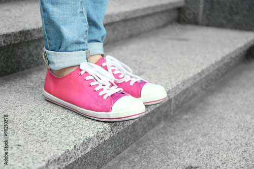 Female feet in pink gumshoes on stone stairs