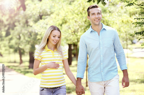 Young pregnant woman with husband walking in park