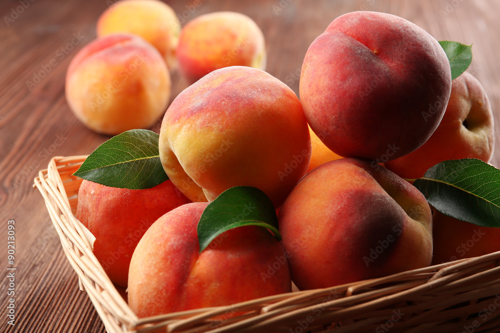 Fresh peaches in wicker basket on wooden table, closeup Fresh peaches in wicker basket on wooden table, closeup