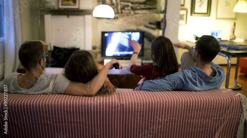 Two couples sitting on the sofa and watching tv
