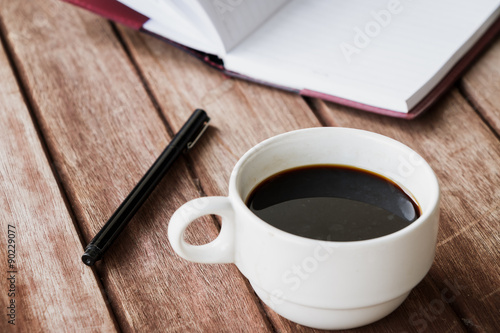 cup of coffee with pen on wooden