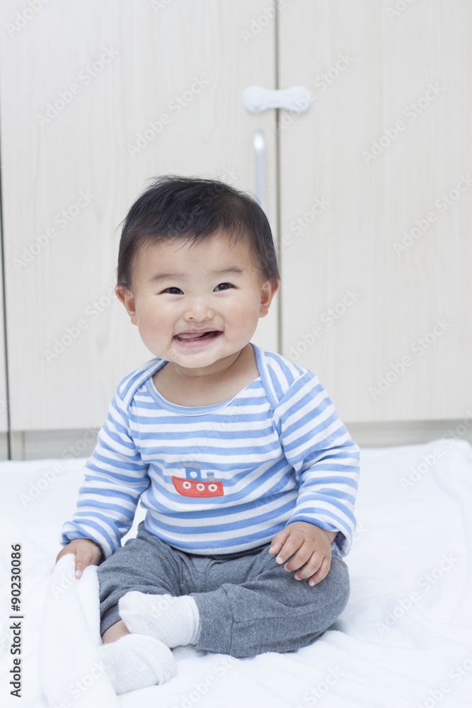 Cute Chinese baby boy sitting on a white blanket Cute Chinese baby boy sitting on a white blanket