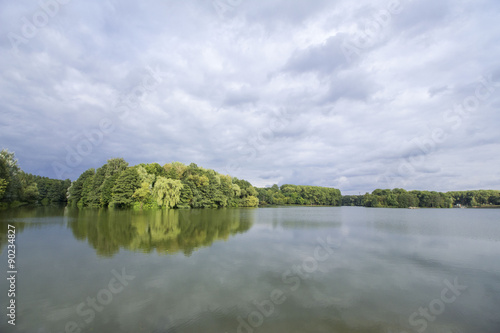 All shades of green lake island view with dramatic sky & water