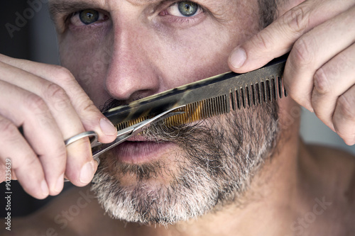 man trimming his beard