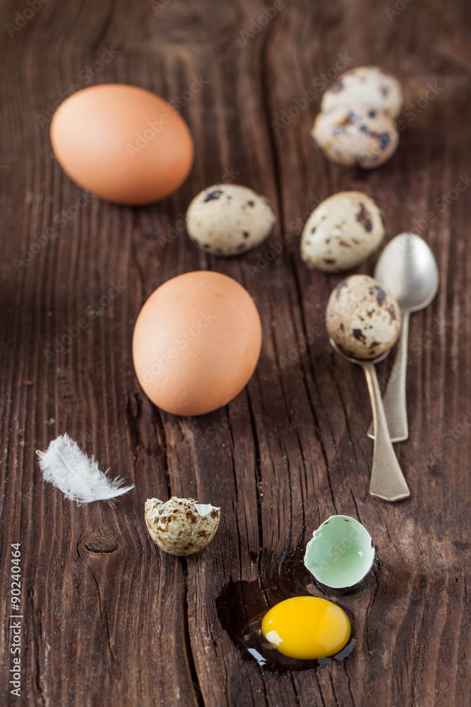 Broken quail egg with the leaked yolk and chicken eggs Broken quail egg with the leaked yolk and chicken eggs