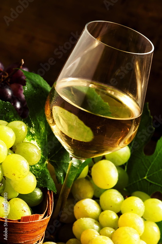 White wine and green grapes in a wicker basket in a wine cellar,