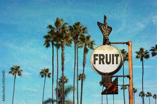 aged and worn vintage photo of fruit sign with palm trees