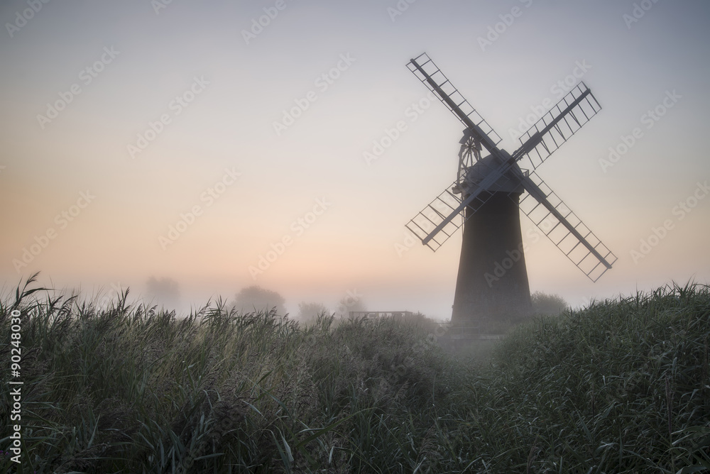Windmill in stunning landscape on beautiful Summer dawn