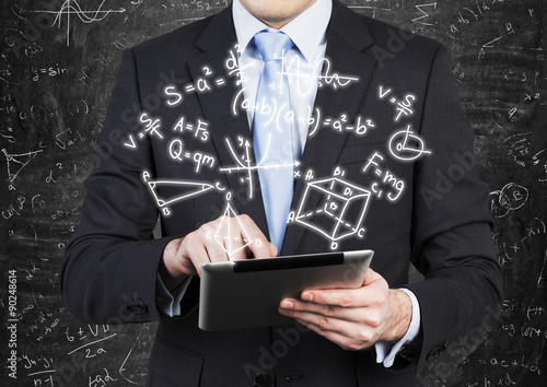 Young man in formal suit is holding a tablet with math formulas projection on the air. photo