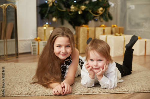 Cheerful girl and boy lying on the floor near a Christmas tree