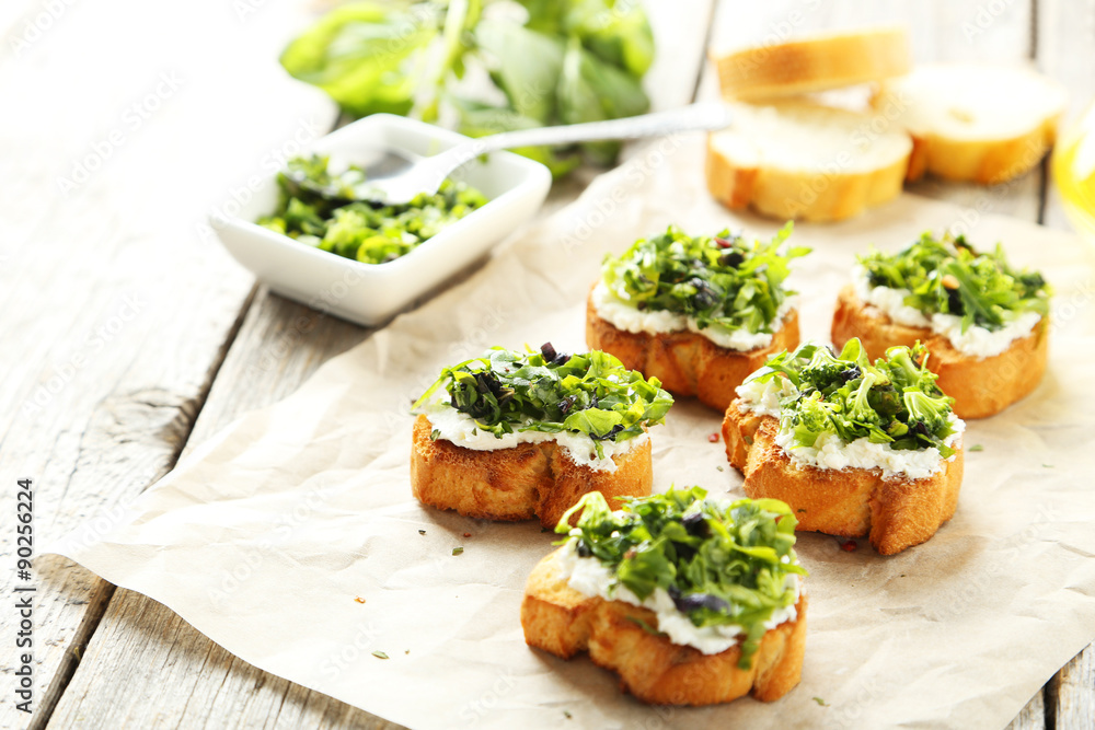 Tasty fresh bruschetta on parchment on grey wooden background