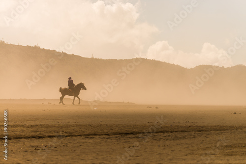horse rider riding on desert in sand storm