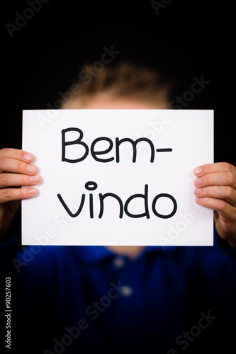 Child holding sign with Portuguese word Bem-vindo - Welcome