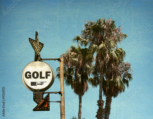 aged and worn vintage photo of golf sign and palm trees
