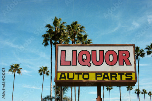 aged and worn vintage photo of liquor and auto parts sign with palm trees