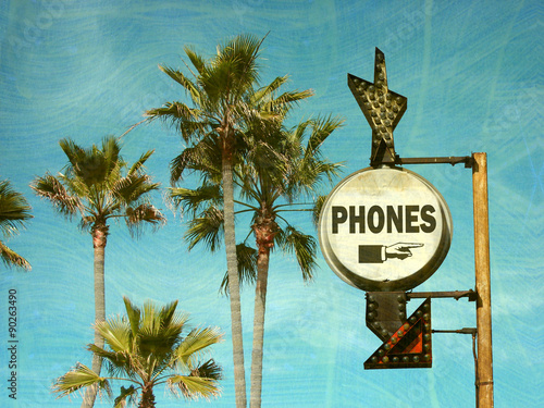aged and worn vintage photo of phones sign with palm trees