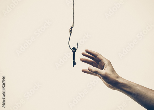 hand trying to get a key hung on a fish hook photo