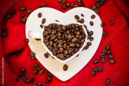 Heart shaped cup with coffee beans on red