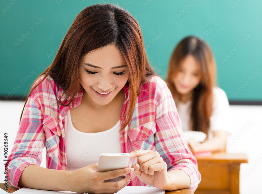 young female student using smart phone in classroom young female student using smart phone in classroom