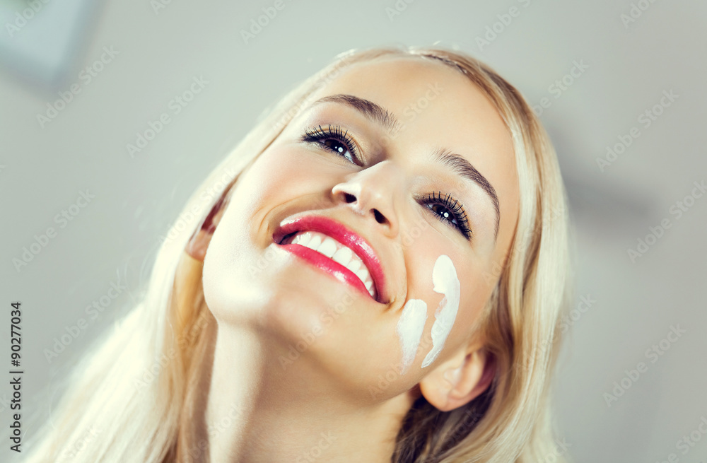 smiling woman applying creme at home - obrazy, fototapety, plakaty 