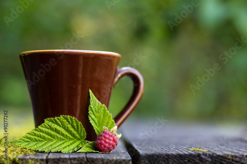 ceramics cup with raspberries on knitted on a wooden table. Shooting in the outdoor.