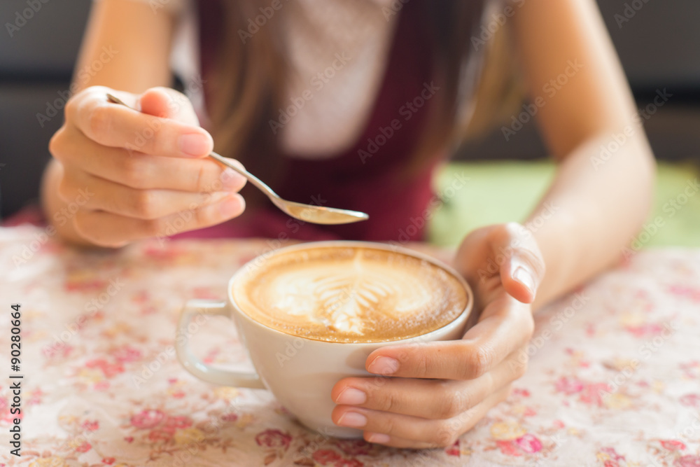 Close up image of woman shaking her favorite tasty hot art latte