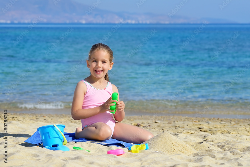 Adorable toddler girl playing with her toys at the beach
