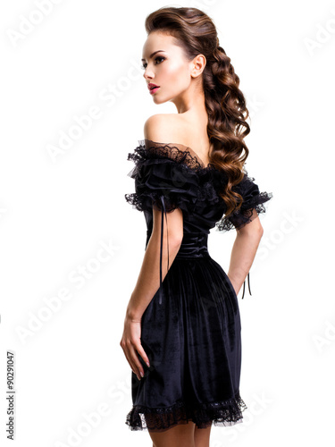 Young sexy woman in black dress posing at studio on white backgr