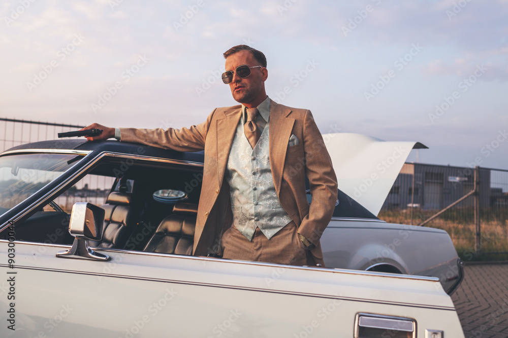 Ταπετσαρία Retro 1970s gangster with pistol leaning against vintage car.