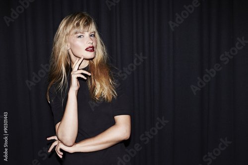 Cool young woman in black posing in studio