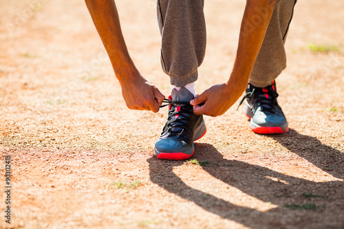 Young man tying a shoelace before jogging