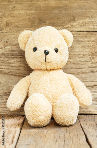 Teddy Bear toy alone on wood background