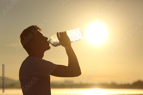 Fitness man silhouette drinking water from a bottle