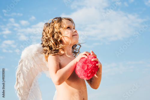 Valokuva little angel holding a heart. St. Valentines cupid girl