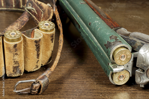 Old double-barreled shotgun open, beside a cartridge box