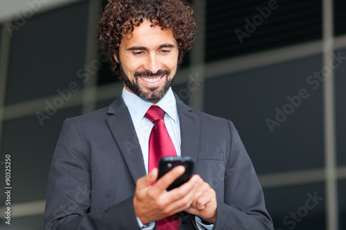 Handsome businessman typing on his mobile phone