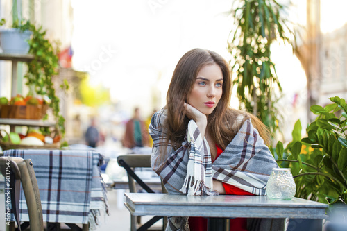 Portrait of a beautiful young girl sitting in a cafe on the stre © Andrey_Arkusha