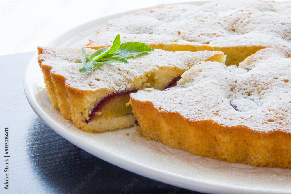 Plum cake dusted with icing sugar, a slice cut Plum cake dusted with icing sugar, a slice cut