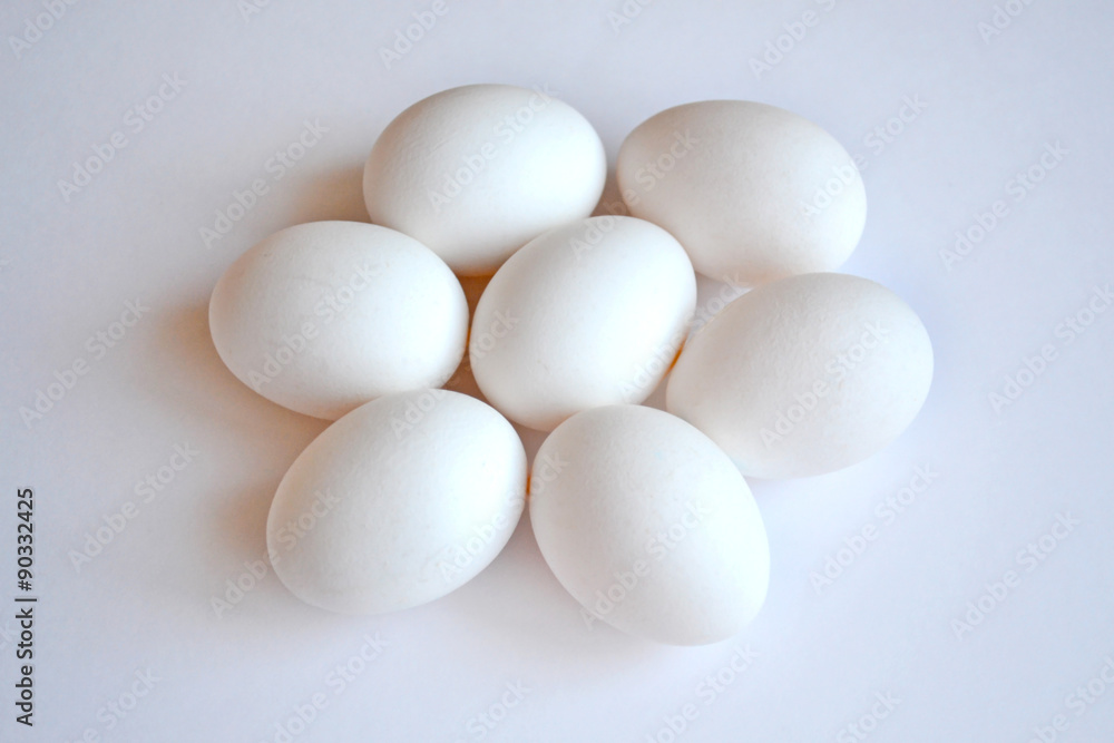 Seven white hen eggs on a white background