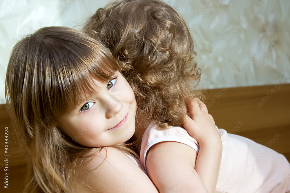 Two adorable little girls hugging each other in the bedroom Two adorable little girls hugging each other in the bedroom